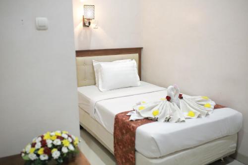 a small room with a bed and a chair at WISMA KUSUMA HOTEL in Kedungdowo