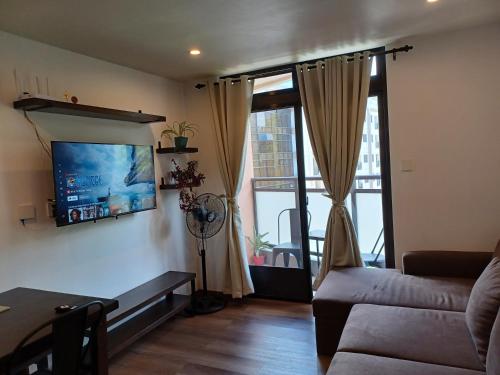 a living room with a couch and a tv on a wall at Gabs CozyHomes at MegaTower IV Condo, City Center Baguio in Baguio