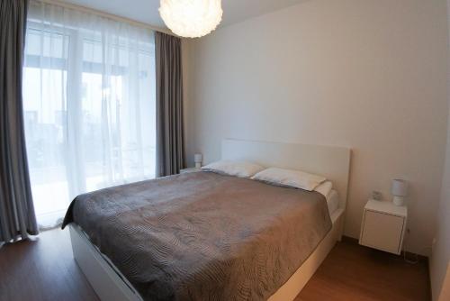 - une chambre avec un lit et une grande fenêtre dans l'établissement Holešovice Delight: Modern Comfort with a Twist in Prague 7, à Prague