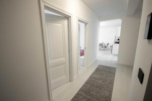 a white door in a white hallway with a rug at DownTown Apartments in Rădăuţi