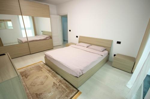 1 dormitorio con 1 cama grande y espejo en DownTown Apartments, en Rădăuţi