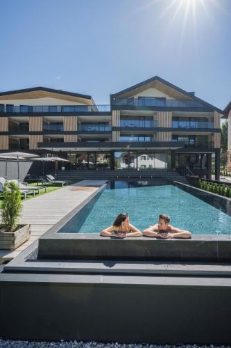 two people in a swimming pool in a building at Montanaris Alpine - Active - Relax in Villabassa