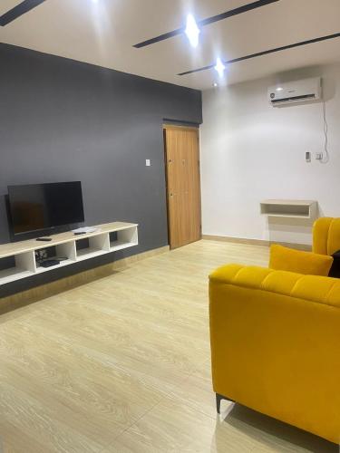 a living room with a yellow couch and a flat screen tv at THE VILLA ABUJA in Abuja