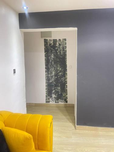 THE VILLA ABUJA في أبوجا: أريكة صفراء في غرفة المعيشة مع لوحة