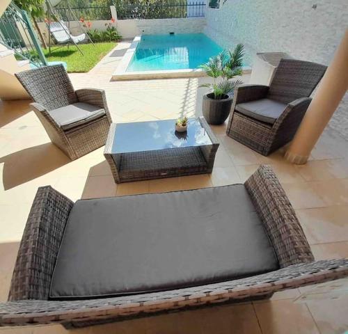 patio z wiklinowymi krzesłami, stołem i basenem w obiekcie Paradise House Ground floor apartment in Villa with private pool and private garden w mieście Abrantes