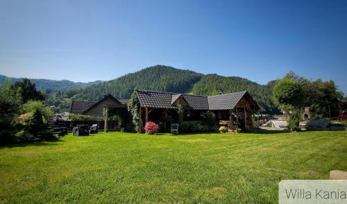 a house on a lawn with mountains in the background at Willa Kania in Szczawnica