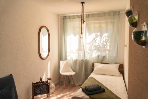 - une chambre avec un lit et une fenêtre avec une chaise dans l'établissement Ferienwohnung Naturini, à Fribourg-en-Brisgau