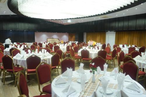 a banquet hall with white tables and red chairs at Grand Mostafa Hotel Ababil in Sylhet