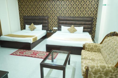 a bedroom with two beds and a chair and a table at Grand Mostafa Hotel Ababil in Sylhet