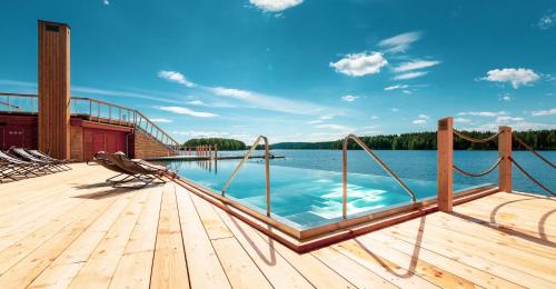 uma piscina num deque de madeira ao lado de uma massa de água em Bella Lake Resort em Kuopio