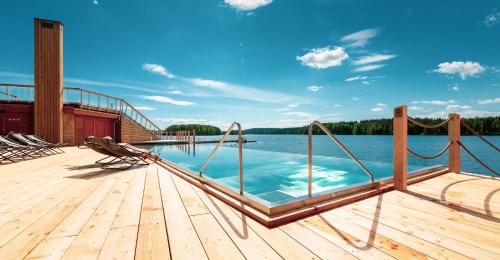 a swimming pool on a wooden deck next to a body of water at Bella Lake Resort in Kuopio