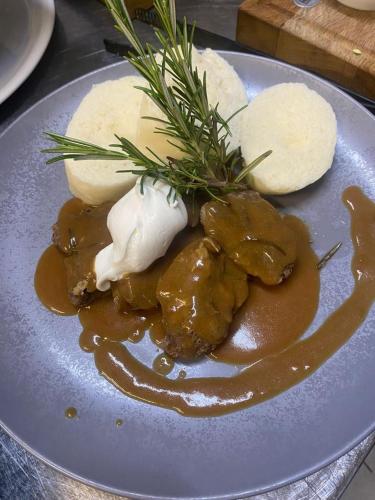 a plate of food with meat and cheese and gravy at Hotel Kresowianka in Konin