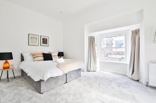 biała sypialnia z łóżkiem i oknem w obiekcie StayRight Spacious Apartments with Private Parking- 15-Minute Stroll to Town Centre w Cardiff