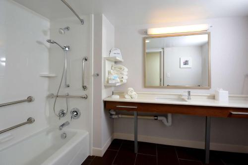a bathroom with a sink and a mirror and a tub at Hampton Inn Charlotte North Lake Norman in Cornelius