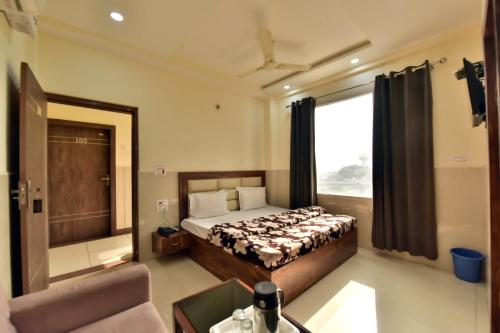 a bedroom with a bed and a couch and a window at Royal Inn in Jammu
