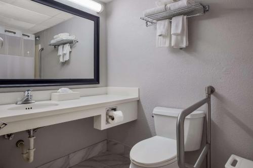 a bathroom with a toilet and a sink and a mirror at Quality Inn in Toledo