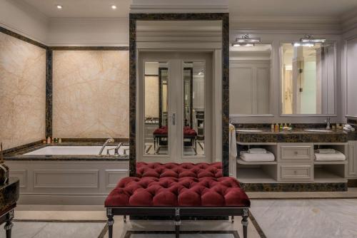 a bathroom with a tub and a red velvet bench at Hilton Tashkent City in Tashkent