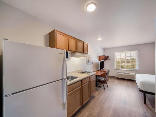 a kitchen with a white refrigerator and a table at WoodSpring Suites Fort Worth Trophy Club in Trophy Club
