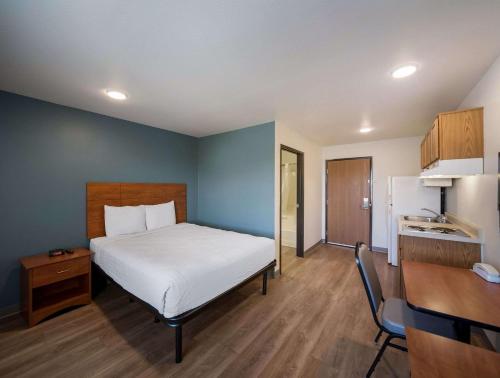 Habitación con cama, escritorio y cocina. en WoodSpring Suites Fort Worth Trophy Club, en Trophy Club