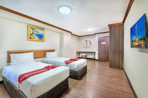 a hotel room with two beds and a table at Nasa Bangkok in Bangkok