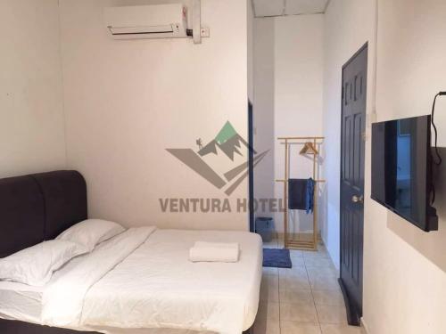 Ventura Hotel and Tours في غُوا موسانغ: غرفة نوم بسرير وتلفزيون في غرفة