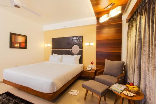 Habitación de hotel con cama y silla en Hotel Cosmopolitan en Ahmedabad