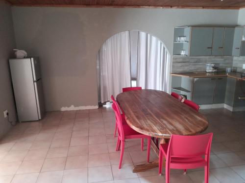 cocina con mesa de madera y sillas rosas en Park guesthouse, en Piet Retief