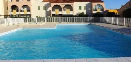 une grande piscine bleue devant un immeuble dans l'établissement Maisonnette 5 personnes avec belle terrasse, Parking 5JRD20, au Barcarès