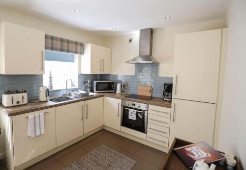 a kitchen with white cabinets and a stove top oven at Seafront Sanctuary Ballycastle in Ballycastle
