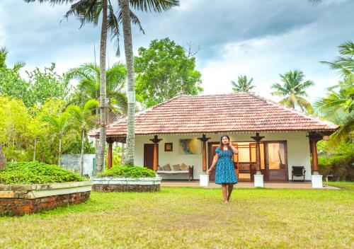 a woman in a blue dress standing in front of a house at Beachside Pool Villa - Karthiyayini by VOYE HOMES in Turavūr