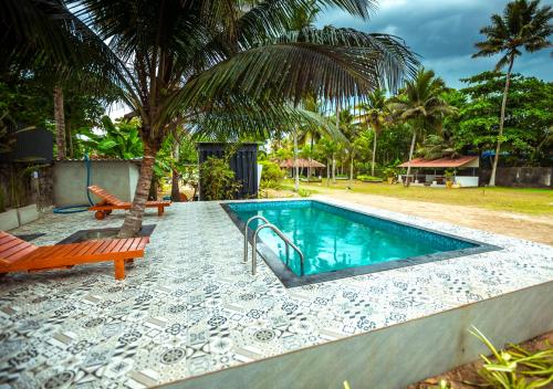 a swimming pool with a bench and a palm tree at Beachside Pool Villa - Karthiyayini by VOYE HOMES in Turavūr