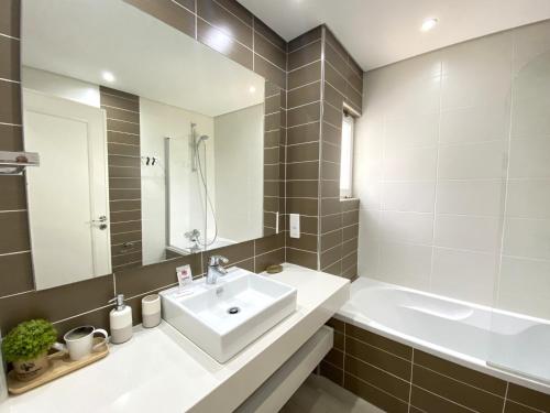 a bathroom with a sink and a tub and a mirror at Albufeira Balaia Golf Vilage 3 With Pool by Homing in Albufeira