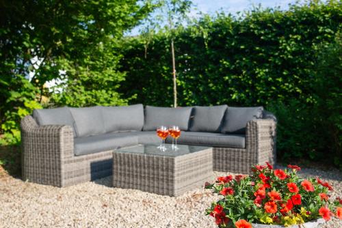 a couch and a table in a yard with flowers at Le Temps d'une Fugue in Lierneux