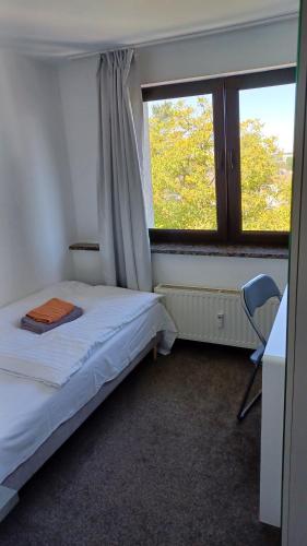 a bedroom with a bed and a desk and a window at Triple Twenty in Eschweiler