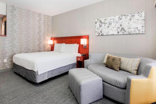a hotel room with a bed and a chair at Courtyard by Marriott Dallas Arlington South in Arlington