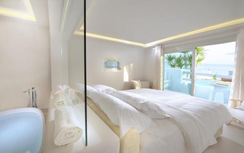a white bedroom with a view of the ocean at Nissaki Boutique Hotel in Platis Yialos Mykonos