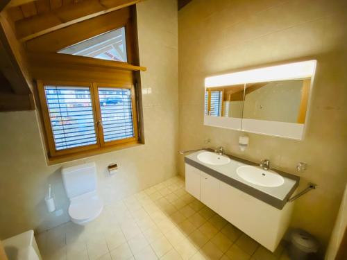 uma casa de banho com um WC, um lavatório e um espelho. em LakeSide Villa - 18 em Niederried