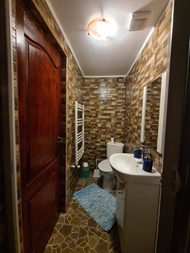 a bathroom with a toilet and a sink and a door at Maricom Home in Zărneşti