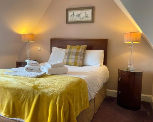 um quarto com uma cama com lençóis amarelos e 2 candeeiros em The Speyside Hotel and Restaurant em Grantown-on-Spey