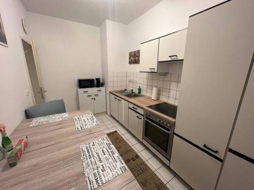una cocina con armarios blancos y una mesa de madera en una habitación en Lichtung Appartement - *WLAN**Netflix**Stadion-Nah* en Leipzig