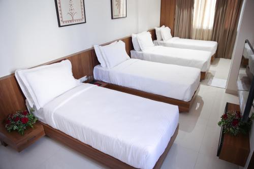 two beds in a hotel room with white sheets at Lords Eco Inn, Ambaji in Ambaji