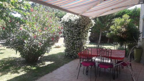 a red table and chairs under a canopy in a garden at Cosy en Provence in Maillane