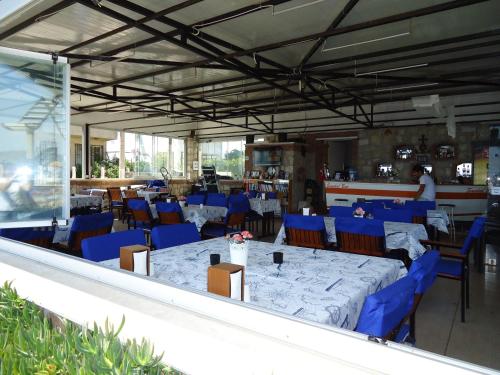 a dining room with blue chairs and tables in a building at Bells Motel in Seferihisar