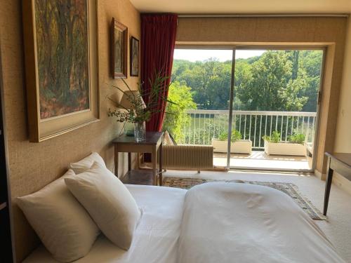 a bedroom with a bed with a view of a balcony at Les Etangs in Ville-dʼAvray