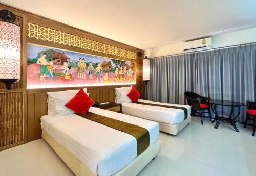 a hotel room with two beds and a table at Nak Nakara Hotel in Chiang Rai