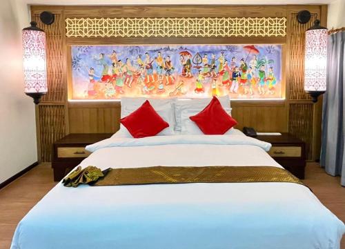 a bedroom with a large white bed with red pillows at Nak Nakara Hotel in Chiang Rai