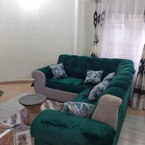 ein Wohnzimmer mit einem grünen Sofa und einem Tisch in der Unterkunft Aura's Airbnb in Busia