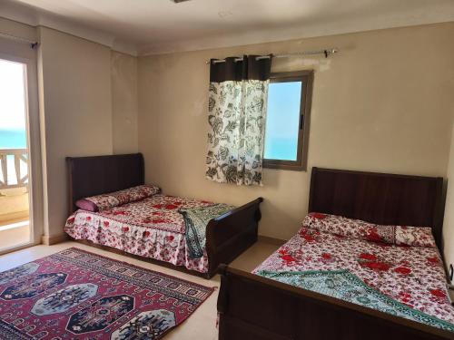 two beds in a room with a window at شقة مصيف الاسكندرية - البيطاش بيانكي in Alexandria