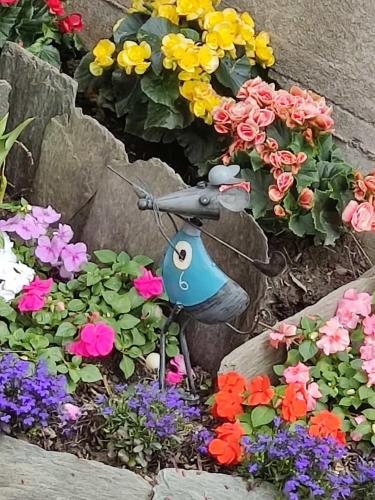 a small bird statue in a garden of flowers at Tirano Express luxury Apartment in Tirano