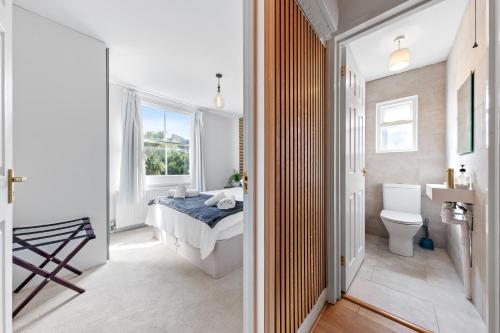 a bedroom with a bed and a bathroom with a toilet at Chelsea Maisonette in London